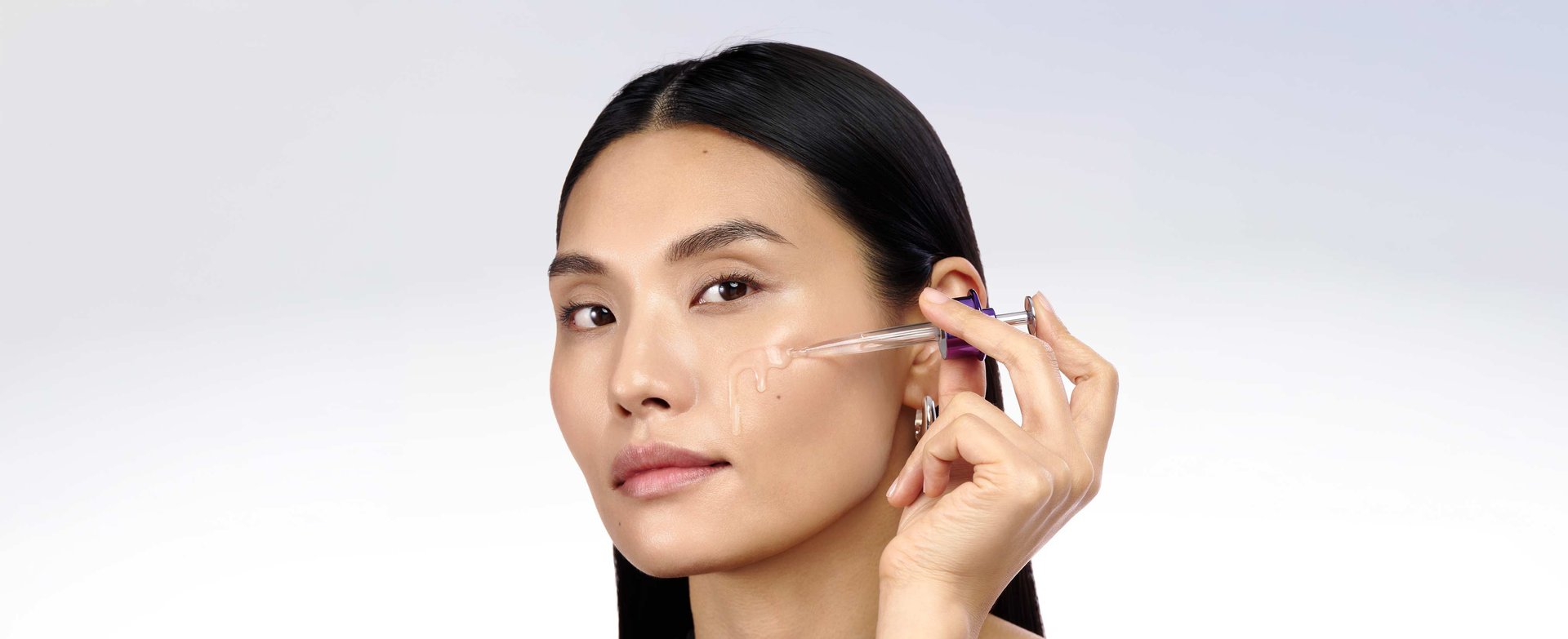 Close-up of model applying lightweight PDRN and Hyaluronic Acid serum to target deep wrinkles, facilitating optimal skin surface absorption 3,000x smaller than pore size.