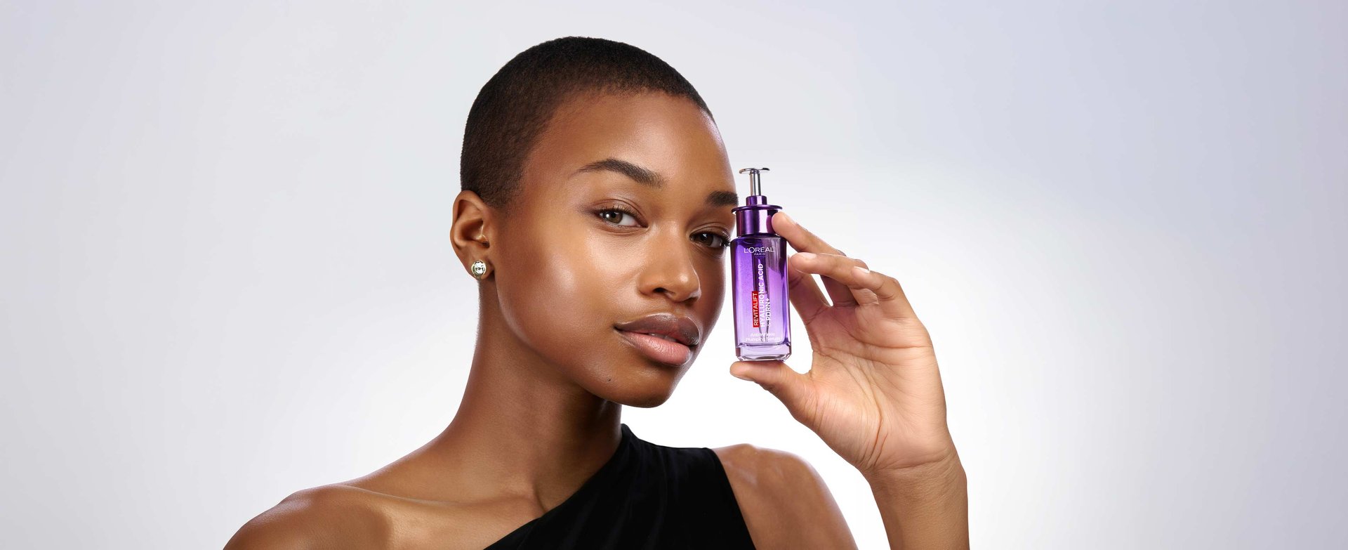 Model showcasing L'Oréal Paris Revitalift Filler bottle, formulated with animal-free bio-fermented PDRN nucleotides and multi-molecular HA to stimulate skin glow, elasticity, and epidermal replumping.