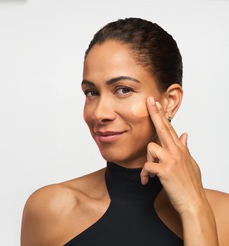 A woman with a radiant complexion applying a dermatologically tested serum, illustrating the clinical application of Revitalift for hyperpigmentation and dark spot correction.
