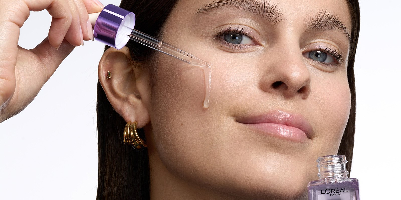 A woman applying L’Oréal Paris Revitalift serum to target fine lines, part of a scientifically validated daily anti-aging skincare routine.
