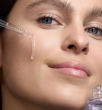 A woman applying L’Oréal Paris Revitalift serum to target fine lines, part of a scientifically validated daily anti-aging skincare routine.